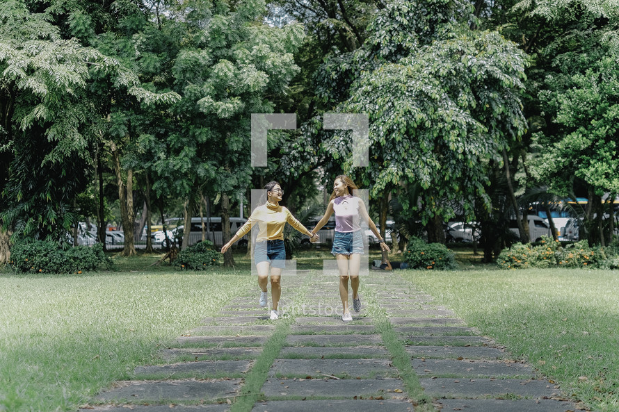 teen girls walking holding hands 