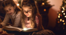 Young girls reading the bible with a golden light illuminating her face