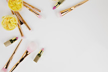 lipstick, makeup brushes, and yellow flowers
