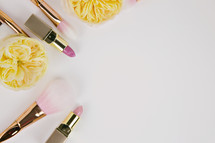makeup brushes, gold flowers, and pink lipstick 