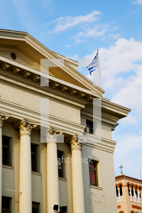 Greek flag flying at the top of a historical building 