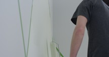 Painting designs onto bedroom wall with paint roller - side profile