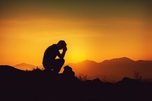 Man praying silhouette with sunset background