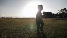 A young happy boy running and playing in sunset in cinematic slow motion.