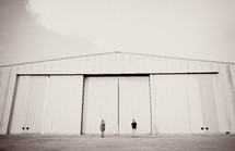 A couple stands in front of an airplane hangar