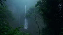 Mystical hazy and wet rainforest with giant waterfall in the distance