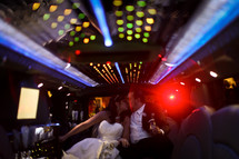 bride and groom kissing at the back of a limo