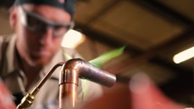 Pipefitter using an oxyacetylene torch for brazing on copper