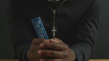 Black Clergyman Holding Bible and Praying to God in Church