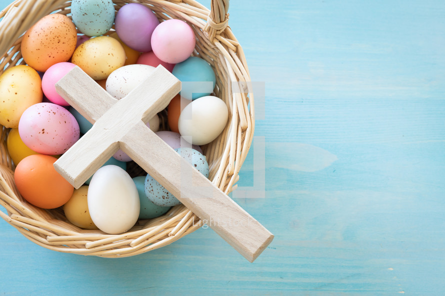 Basket of Easter eggs and cross on a blue background