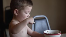 Young boy, child eating breakfast cereal at table.