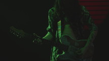 Rock Musician Playing the Guitar in Dark Studio with Neon Illumination