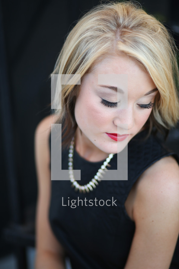 blonde female model in a black dress with closed eyes 