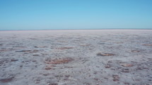 Aerial drone shot of salt flat, dry lake covered with white crust. Daytime, no people, unique natural landscape