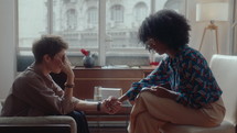 Female African-American psychologist holding hands with upset patient, listening to her and supporting during consultation. Side view
