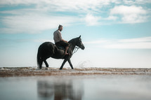 Horse riding on a beach, equestrian man riding on a horse