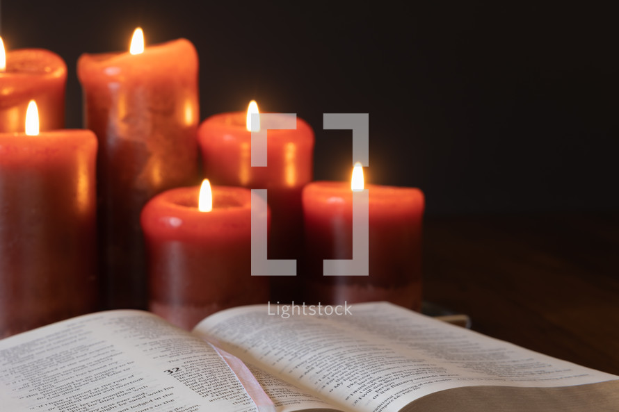 red candles burning near a Bible 