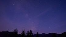 The night sky with stars is covered with clouds, the silhouette of the forest