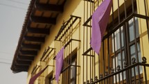 Windows Decorated With Lilac Cloth During Holy Thursday Of Semana Santa In Antigua, Guatemala. Low Angle Shot
