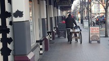 man pushing a cart down a sidewalk 