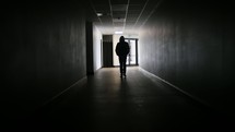 man walking down a dark hallway