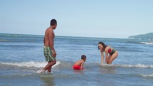 Mother and Father playing and fooling around with his toddler son at the ocean beach having fun. Multi ethnic family playing with his young son at the beach, priceless parenthood moments.
