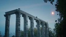 Old ruins of temple at night with moon glow in background