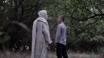 A young teen boy meets Jesus Christ in nature and trees in cinematic slow motion.