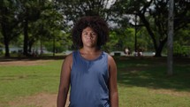 portrait of confident young black woman at the park looking serious at camera independent african american female in outdoors background slow motion
