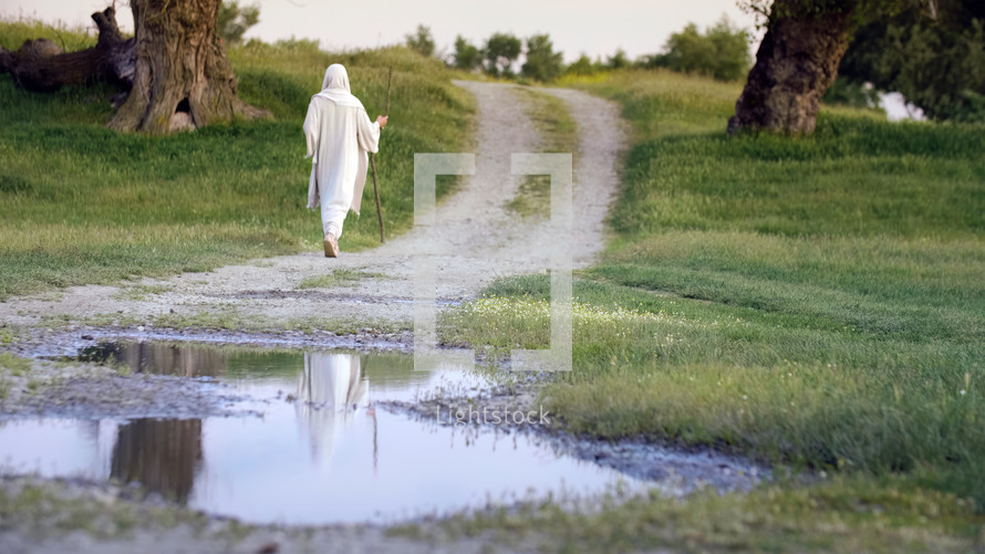 Jesus Christ walking on a country road with a pond reflection.
