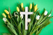 Cross on a bed of yellow and white tulips on a green background