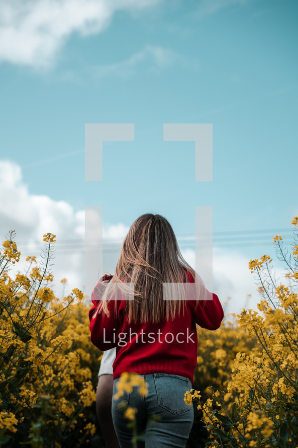 Freedom in nature, girl walking in a field, yellow rapeseed blue sky landscape photo