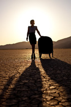 silhouette of a woman standing beside a chair on parched earth