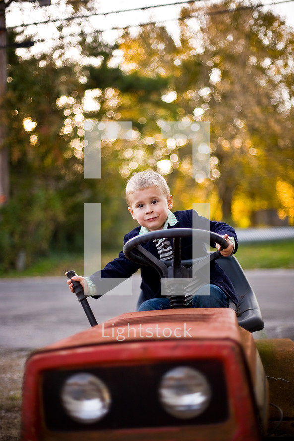 toddler boy riding a lawn mover