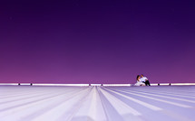 distant bride and groom on a roof under a purple sky