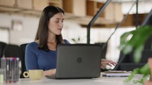 Focused white businesswoman working on laptop computer in home office. 