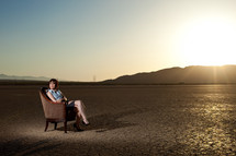 woman sitting in a chair on parched earth