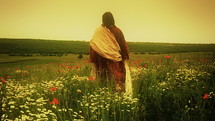 Christ walking alone through poppy field.