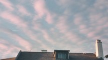 Clouds above building with bird flying over head