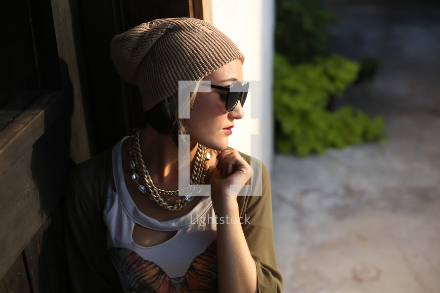 teen girl posing for senior portraits in a wool cap and sunglasses 