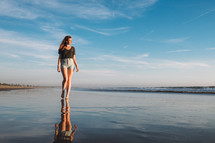 young woman walking bare foot on wet sand on a beach 