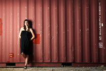 woman in a black dress standing in front of a warehouse 