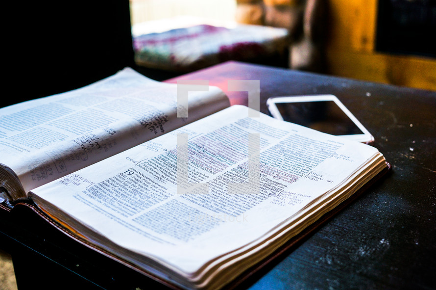an open Bible and cellphone on a table 