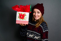 a teen girl in a sweater holding a Christmas gift 