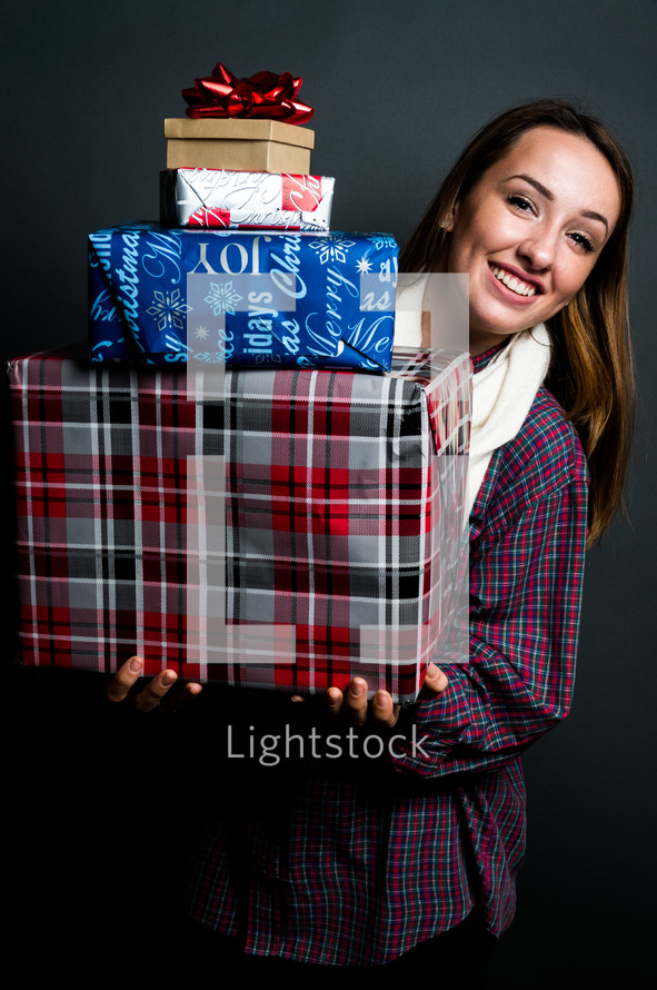 teen girl holding a stack of wrapped Christmas gifts 