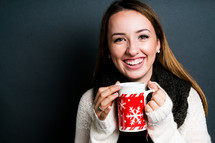 a smiling young woman holding a mug 