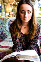 teen girl reading a Bible on a couch 
