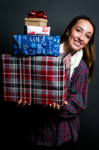 teen girl holding a stack of wrapped Christmas gifts 