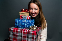 a teen girl holding a stack of Christmas gifts 