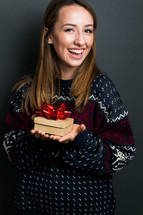 a smiling young woman holding a Christmas gift 